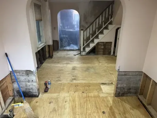 Hallway with lower wall sections removed and the subfloor exposed