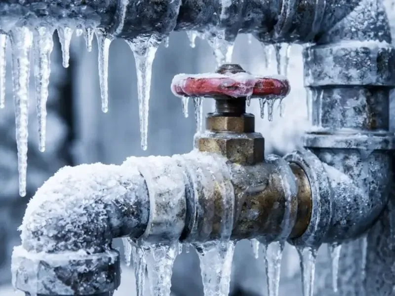Ice and icicles covering exposed pipes and a shutoff valve