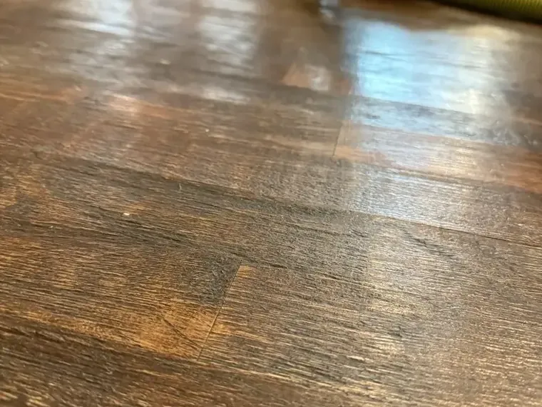 Moisture reflecting across water-affected wood floorboards