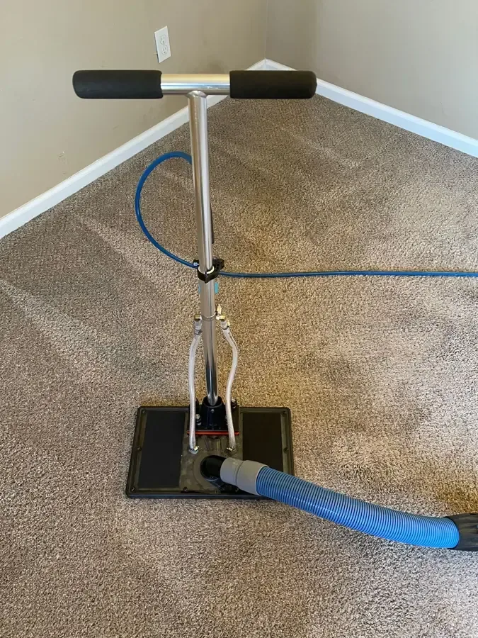Carpet extraction wand connected to a blue recovery hose